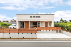 周囲の自然とも調和する素材を用いた、シンプルなスクエアフォルムの外観。庭のフェンスはウッドデッキや軒天井とコーディネートした