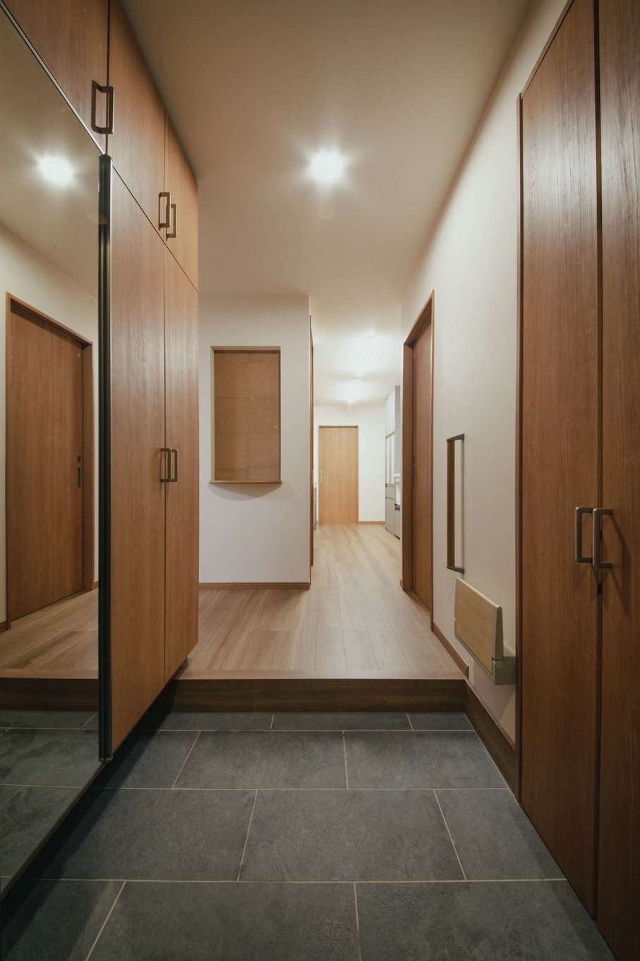 未来創建【二世帯住宅、省エネ、間取り】6人家族共用の玄関ホールはゆったりと。大容量のシューズクローゼットも完備。腰かけて靴を履けるよう、折りたたみのベンチも造作。ここから一直線に水回りへとつながる動線が便利