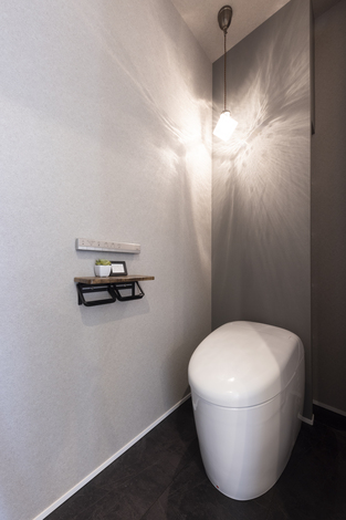 シンプルでモダンなデザインのトイレ。落ち着いた色調の空間に、洗練された照明が優雅な雰囲気を演出している。