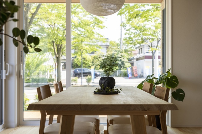 自然光が降り注ぐダイニングスペース。大きな窓から見える緑が、居心地の良い空間を演出しており、リラックスした食事の時間を提供する。