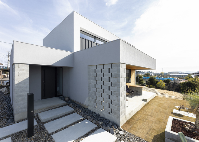 角度を変えて外観を眺めると、表情豊かなフォルムに圧倒される。透かし彫り風のブロックで玄関ポーチやテラスを覆ったことで、プライバシーを確保できた