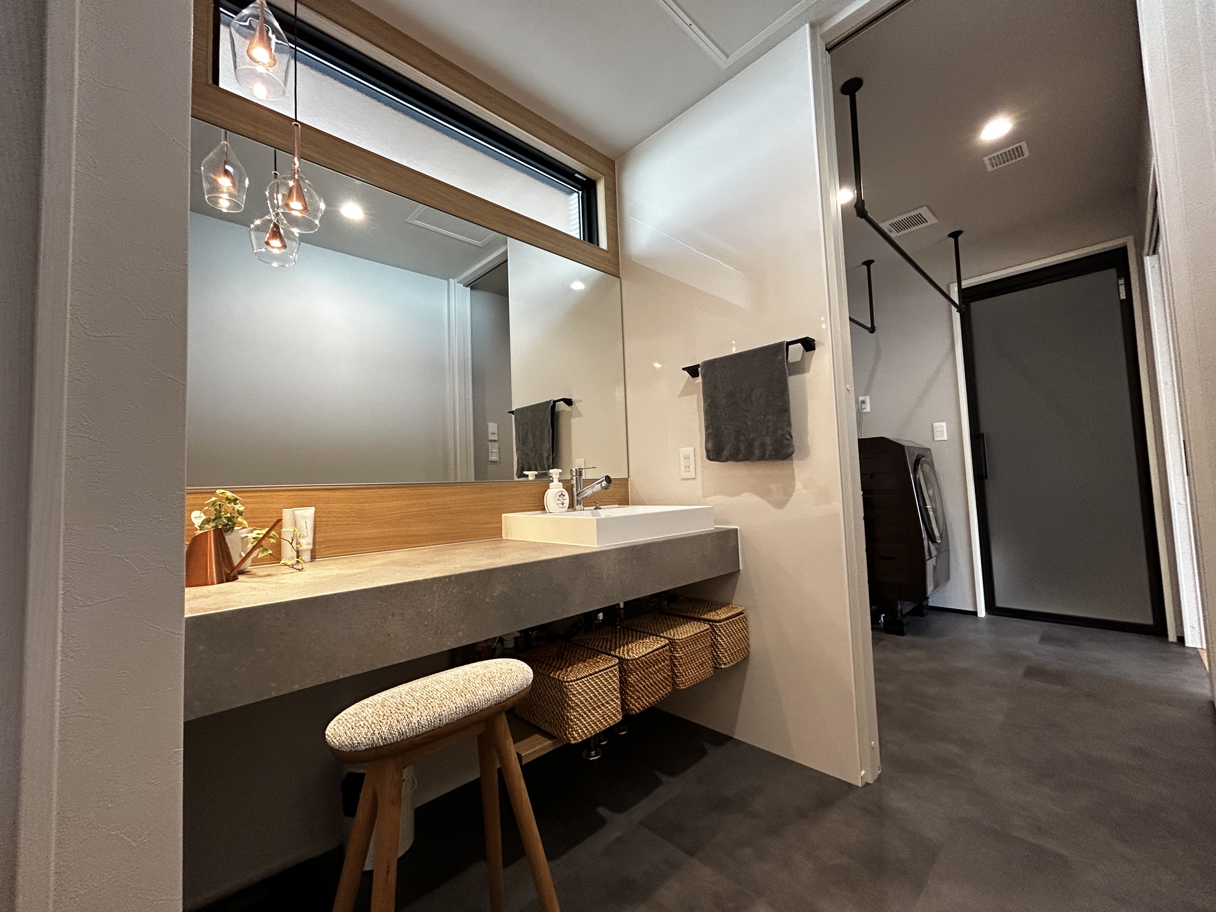 パナソニックホームズ中部第一支社 愛知第一支店・愛知第二支店｜シンプルで落ち着いたデザインの洗面スペース。大きな鏡と豊富な収納があり、使い勝手が良い。こだわりのホテルライクの照明が雰囲気を演出している。