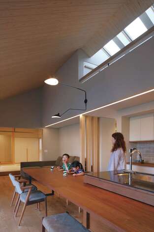 開放感あふれる吹抜けのLDK。ダイニングテーブルと一体化したストレートキッチンを中心に、家族の様子を見渡せるオープンな間取りが特徴