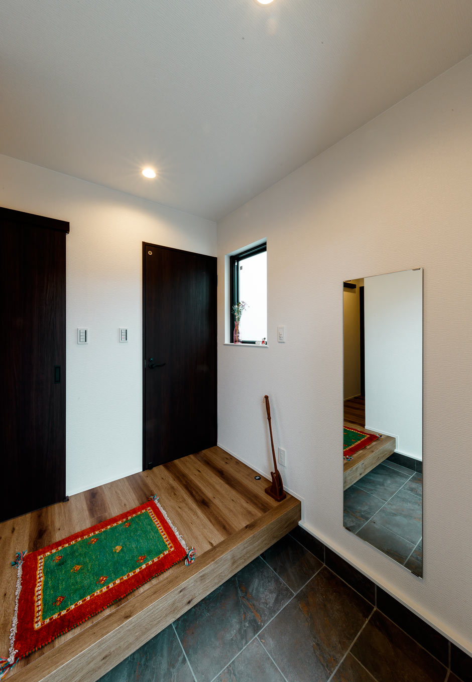 長坂篤建築研究所│nalabo（エヌエーラボ）【デザイン住宅、収納力、建築家】木のぬくもりに満ちた玄関ホール。西側の小窓から十分な光を確保し、暗くなりがちな空間に明るさをもたらす。大きな姿見は靴までチェックできると同時に、空間を広く見せる効果もある