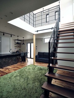 大きな吹き抜けを設けたLDK。吹き抜け部分の壁に大きな窓から太陽の光が降り注ぎ、とても明るい空間に