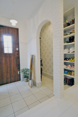 収納たっぷりの玄関ホール。アーチの垂れ壁がやさしい雰囲気を演出。重厚感のある扉もすてき