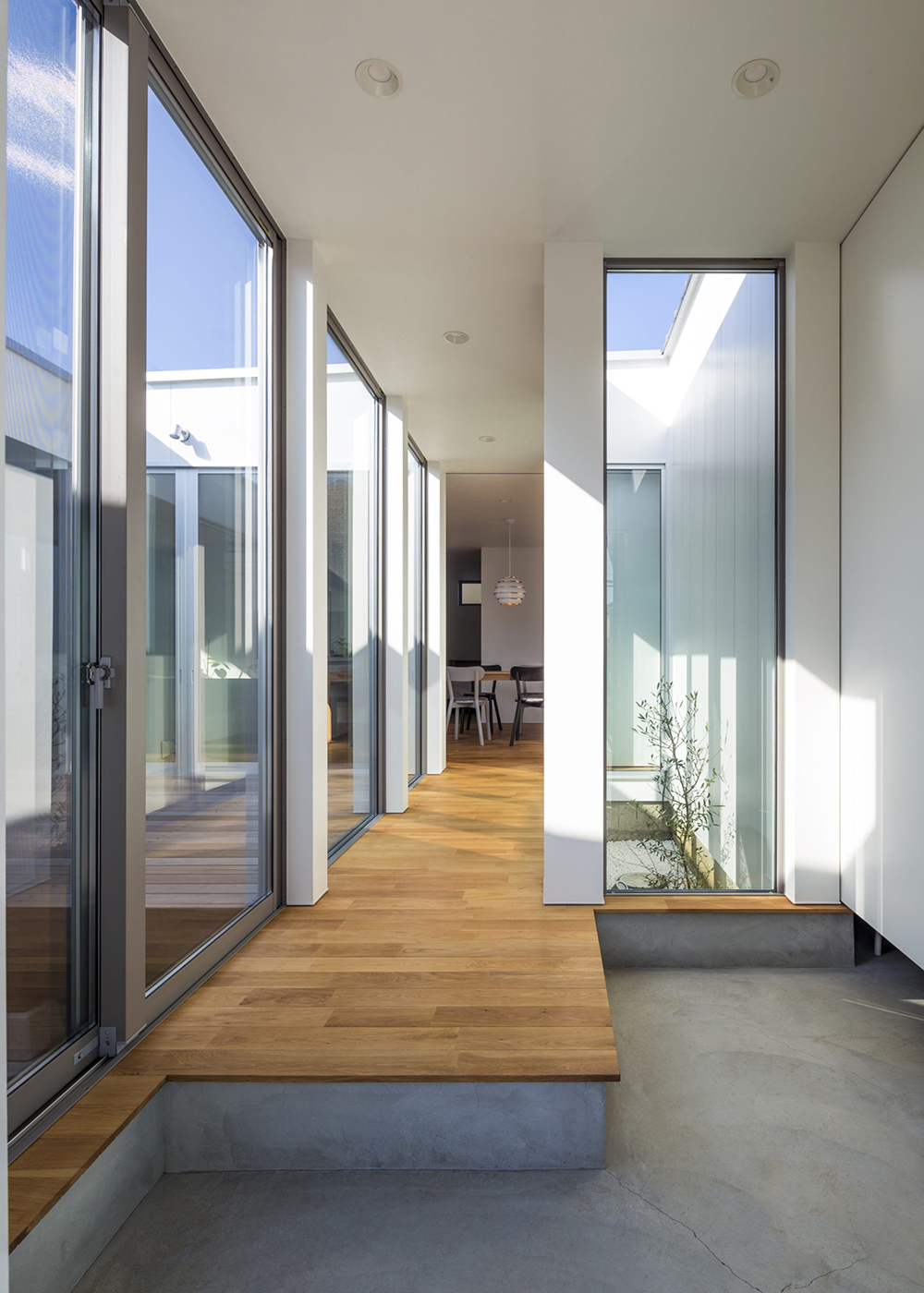 SIMPLE NOTE 豊川スタジオ【夫婦で暮らす、間取り、平屋】通り土間のある広い玄関ホール。大きな窓から中庭やその先の青空へと視線が抜けていき、抜群の開放感を生み出している