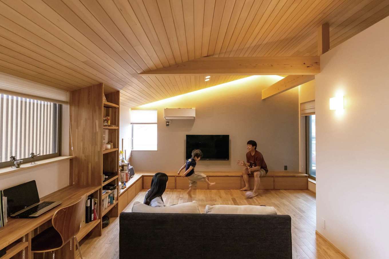 神谷綜合建設 カミヤの家【デザイン住宅、和風、間取り】LLDKでひときわ目を引く勾配天井は、色目がきれいなツガの板張りで仕上げた。リビングの正面は質感のある塗り壁とし、天井に仕込んだ間接照明が美しい陰影を描くとともに、空間に奥行きを生み出す効果も。カーテンの代わりに和紙風の素材を使ったブラインドは、断熱効果のあるハニカム構造。ブラインドを下ろしていても優しい光が室内を満たす。「収納棚は可動棚にするかなど、こちらが気づかない点もちゃんと確認してくれ、安心して任せられました」とご主人