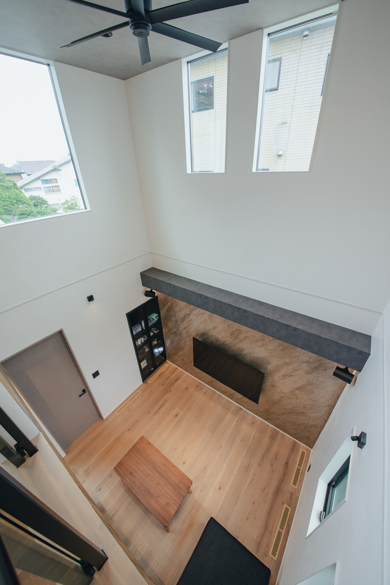 nattoku住宅【デザイン住宅、自然素材、間取り】1階と2階の奥まで光を届ける6畳の吹抜け。開放的でありながら、全館空調による熱交換率に優れた快適空間を実現。テレビの壁は表情豊かなイタリア漆喰「ユーロスタッコ」で、空間のアクセントになっている