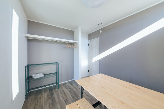 自然光が差し込む明るい居室。オープン収納スペースがあり、シンプルながらも機能的な空間が広がる