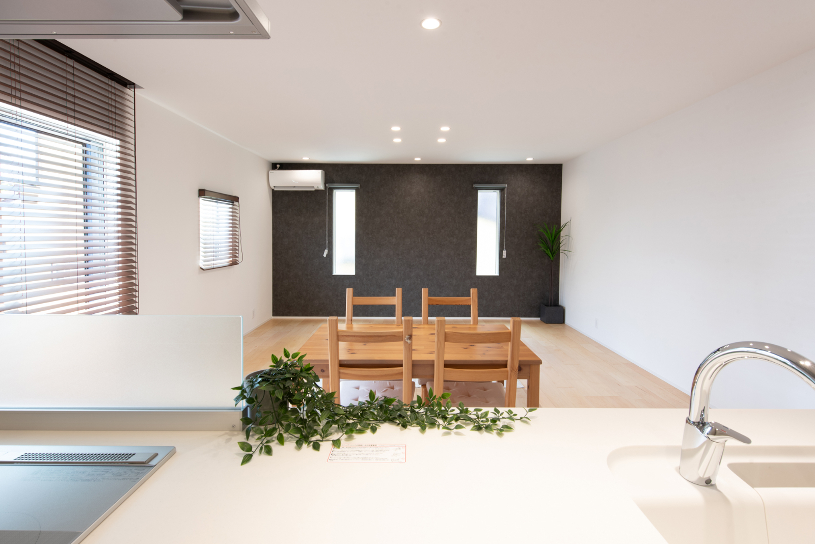 エルフィン｜シンプルで広々としたLDK空間。キッチンからの視界が開け、家族との会話が弾む設計で温かみのあるダイニングセットが魅力。