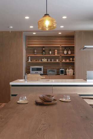 オープンキッチンの収納スペースの壁面の木製パネルはモデルハウスを参考にしたもので、『幹工務店』のオリジナル。照明に木のラインが映え、カフェのようにオシャレな雰囲気