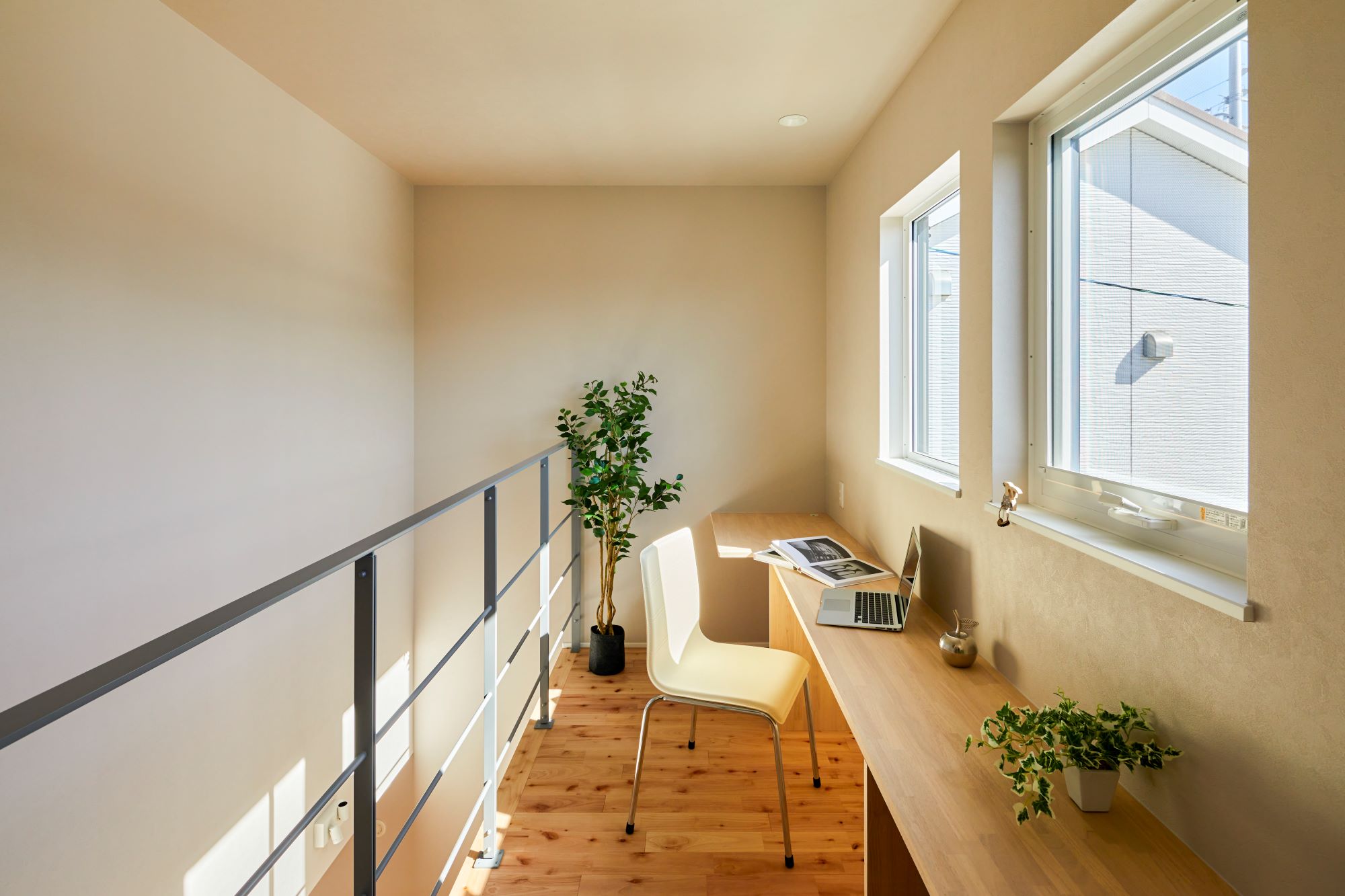 GATE（R+house春日井）｜窓からの自然光が心地よいワークスペース。シンプルなデスクと椅子が配置され、植物を置いてリラックスできる雰囲気を演出している。