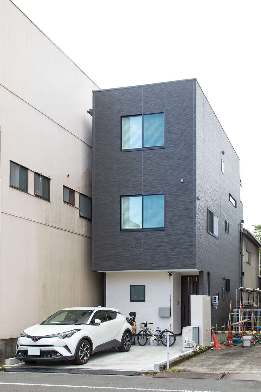 建築システム（狭小住宅専門店）【1000万円台、狭小住宅、インテリア】モノトーンながら暗い印象にならないアイボリーブラックのサイディングを用いた外観。北向きになる正面にも窓を付け、室内に優しい光を届ける