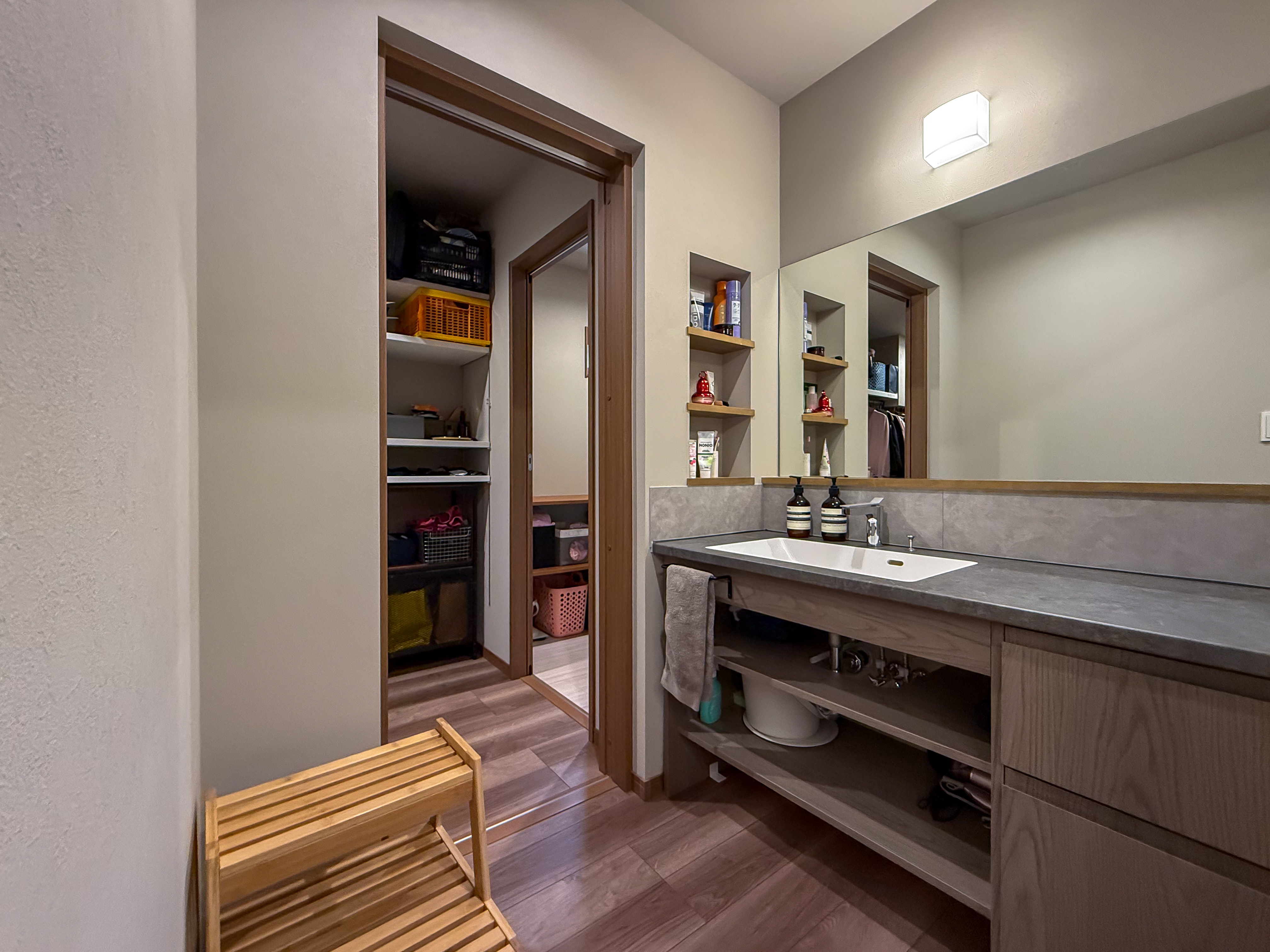 ロイヤルウッド｜広々とした洗面スペースが特徴的で、豊富な収納棚が備え付けられている実用的な設計。明るい照明と清潔感のあるデザインが心地よい。