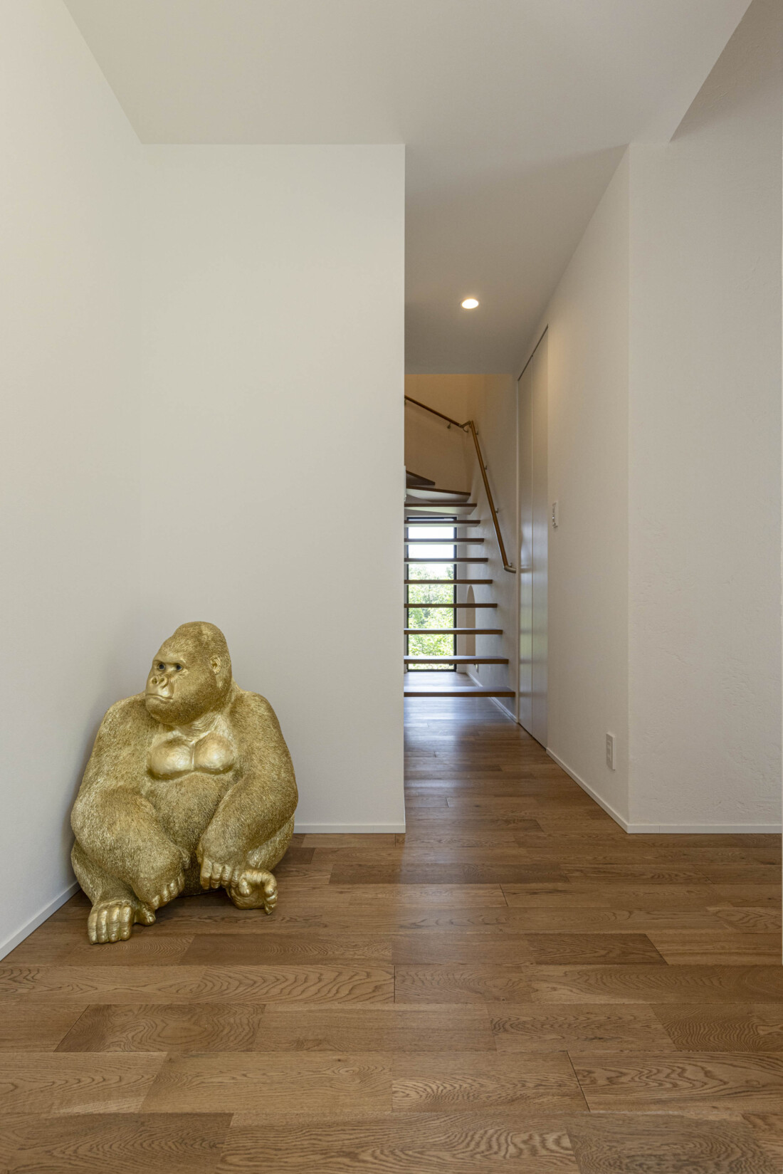 チェックハウス｜階段へと続くシンプルで美しい廊下の一角。無垢材のフローリングとホワイトの壁が調和し、穏やかな空間を演出している。