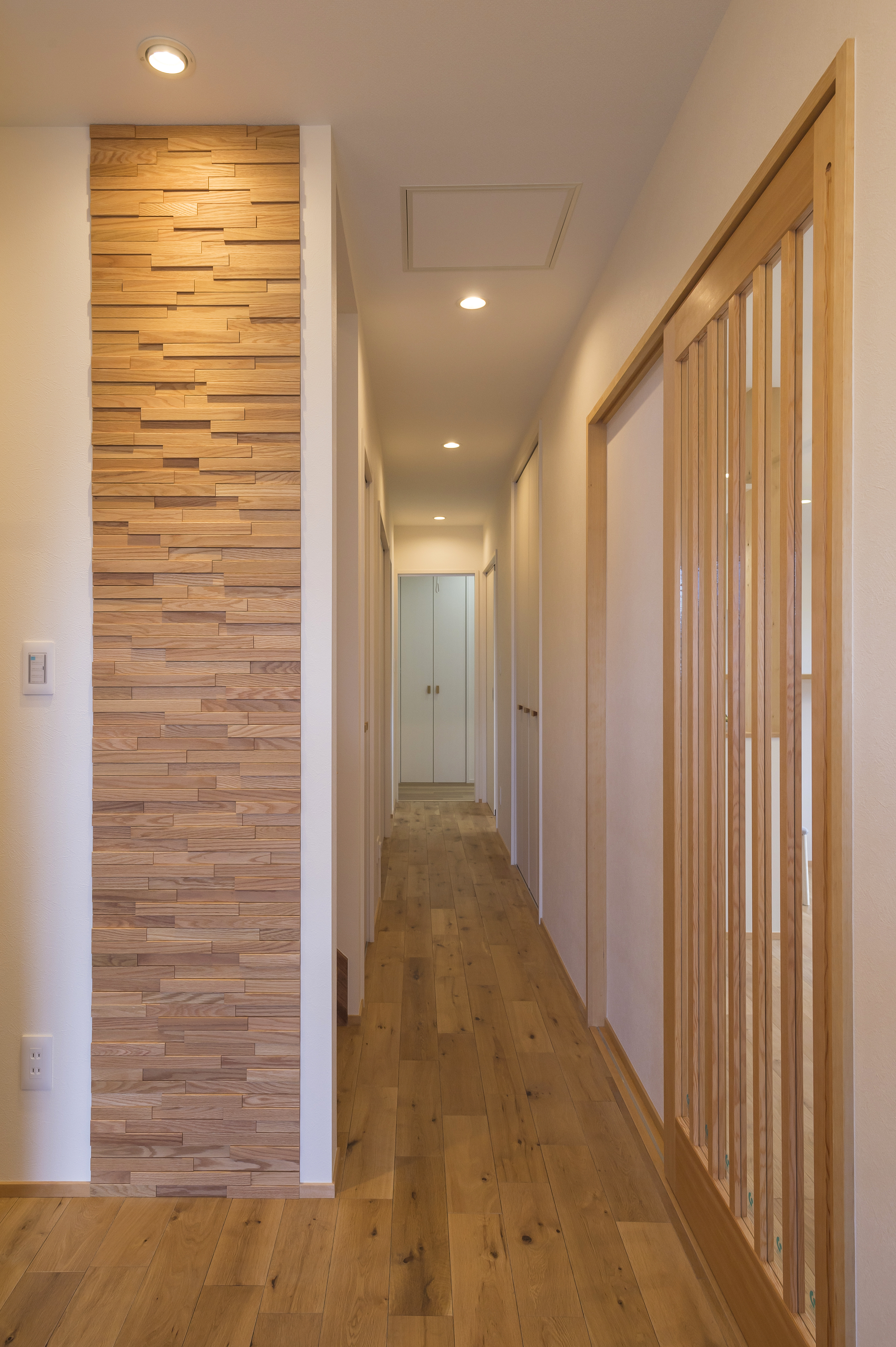 しあわせの住まい一級建築士事務所｜木材をふんだんに使用した温かみのある廊下。シンプルで落ち着いたデザインが魅力的で、照明が柔らかく空間を包み込む。