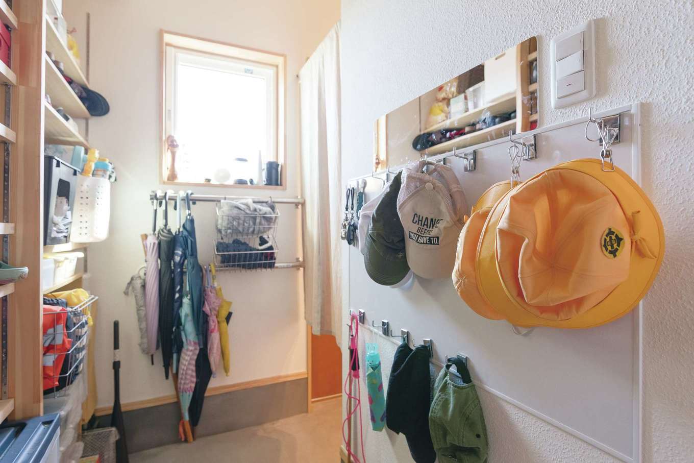 Casa（カーサ）【子育て、間取り、平屋】玄関の壁には巨大なホワイトボードを取り付け、マグネットフックで帽子類をずらり整頓。傘用ラックもAさん自ら設置し、帰宅時に子どもたちが自分で片付けられるようにしている
