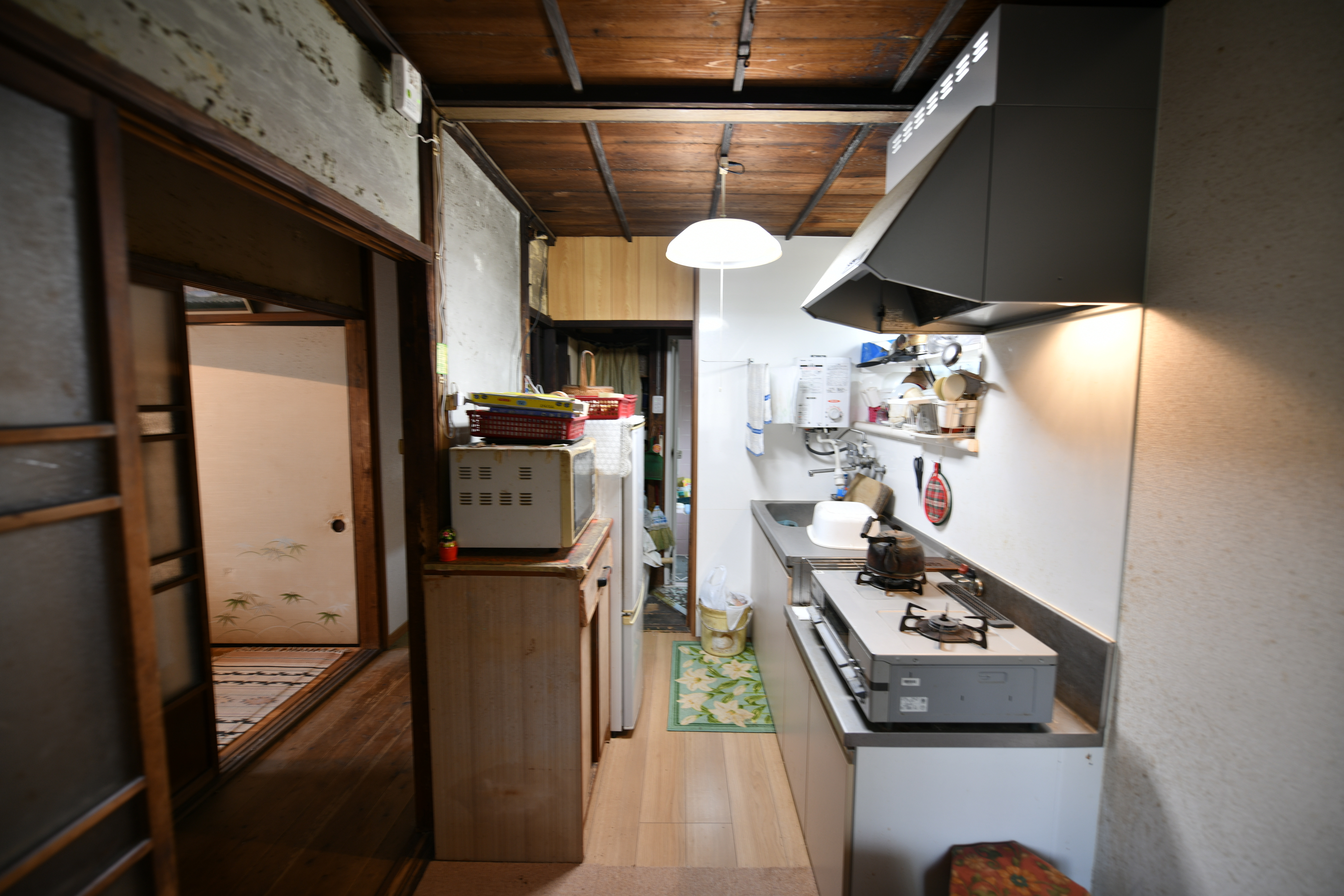 建物の北側にあったダイニングキッチンは、洋室や和室との間に廊下を挟み、家事動線が不便だった。キッチンは壁付けのI列型で、幅は広いがワークスペースや収納スペースが狭くて調理や片付けがしづらい状況だった。