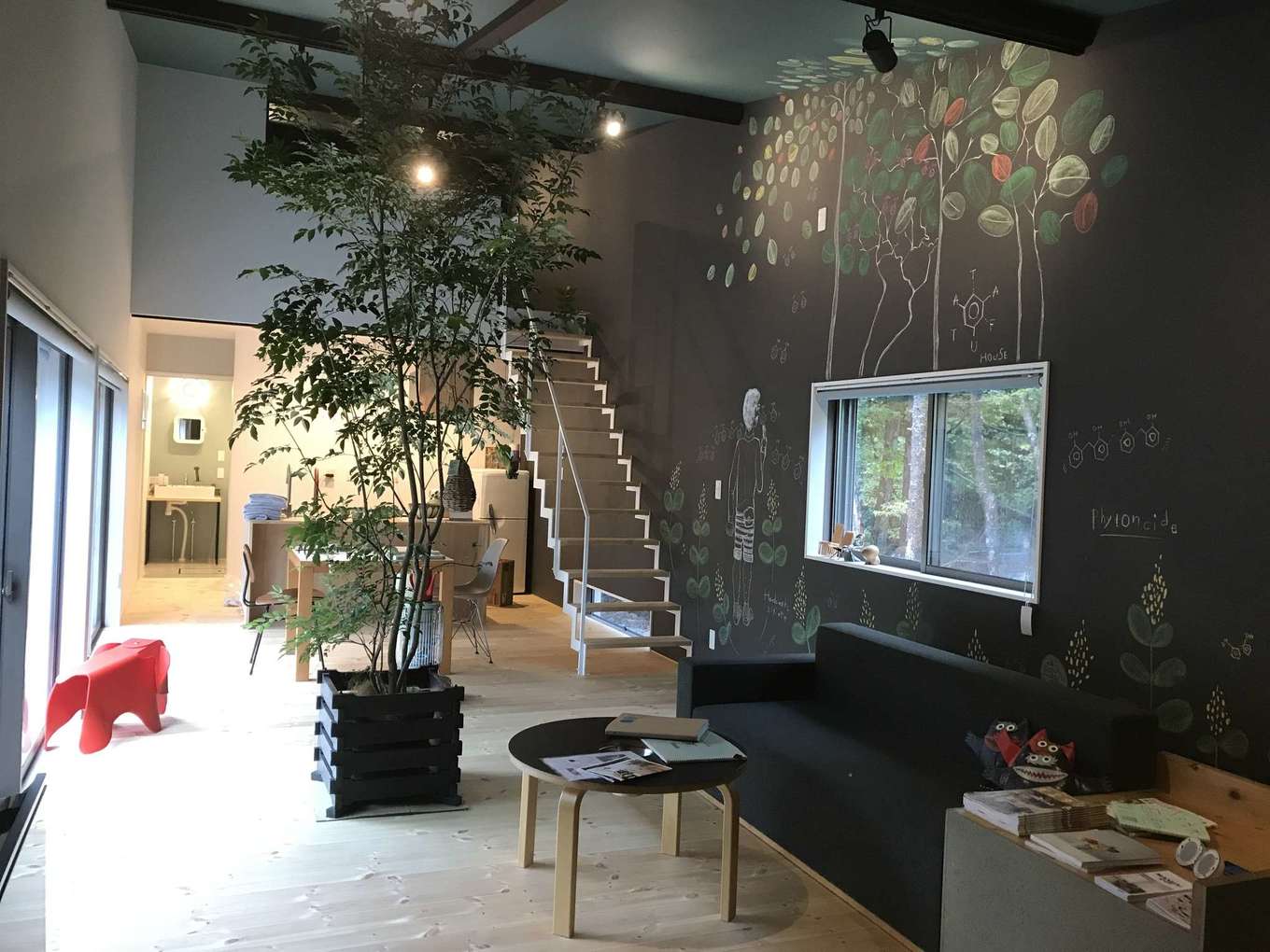 Hands Works（アオイ建築）【1000万円台、趣味、平屋】21畳のLDKは、別荘として使うには十分な広さ。天井が高いため、さらに開放感が増し、ゆったりと寛げる。黒板クロスに描かれた樹木の絵はピンスポットで照らし、インテリアとして楽しむ。階段で上がるロフト付き