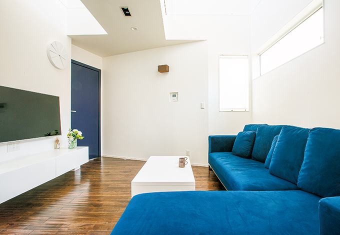 白い空間にネイビーを差し色に。大きなカウチソファ「SARINA」はリビングの主役。人が写り込むほど輝くデザインドア「REVER」は、世界の名だたる五つ星ホテルにも採用されている