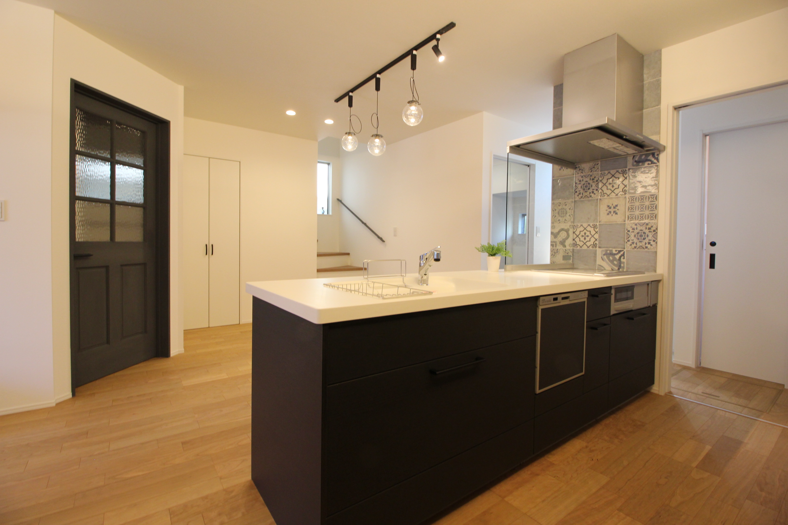 小野田産業～designers house project～｜モダンなデザインのアイランドキッチン。背面のタイルがアクセントを添え、開放感ある空間を演出している。