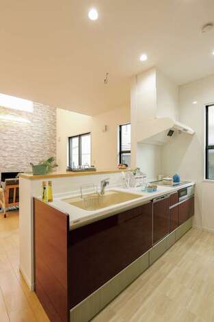 家族の様子を見渡しながら調理できる対面キッチン。ダークカラーのパネルが白を基調とした空間の差し色になっている