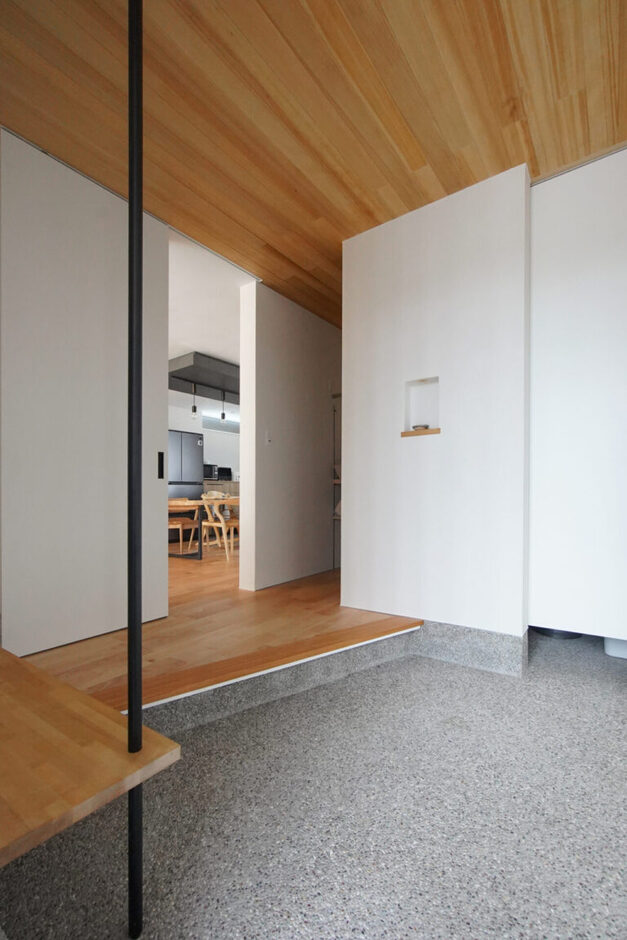 広々とした玄関ホールの壁は、消臭効果や調湿性能に優れた珪藻土の塗り壁仕上げ。天井は落ち着いた風合いが魅力のアガチス、床は優しい木目が美しい西南桜の無垢フローリングで仕上げた、自然素材の美しい空間。