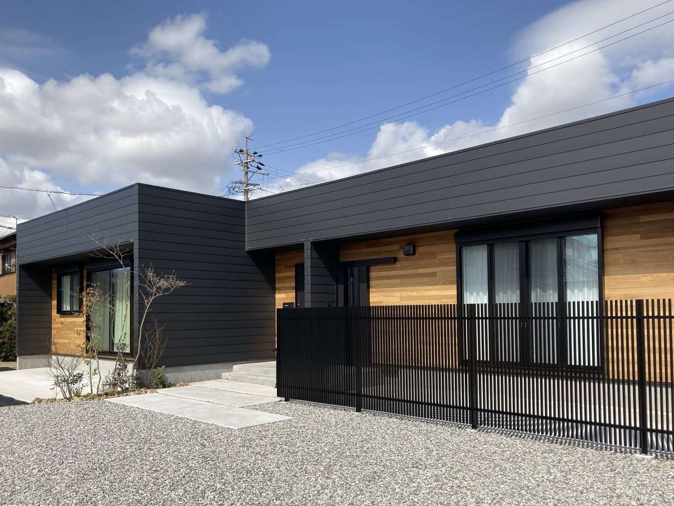 アールスタジオ【デザイン住宅、平屋、インテリア】広い敷地を活かして建てた平屋の外観。黒いガルバリウム鋼板の外壁に、レッドシダーの板張りの壁を組み合わせてアクセントをつけた