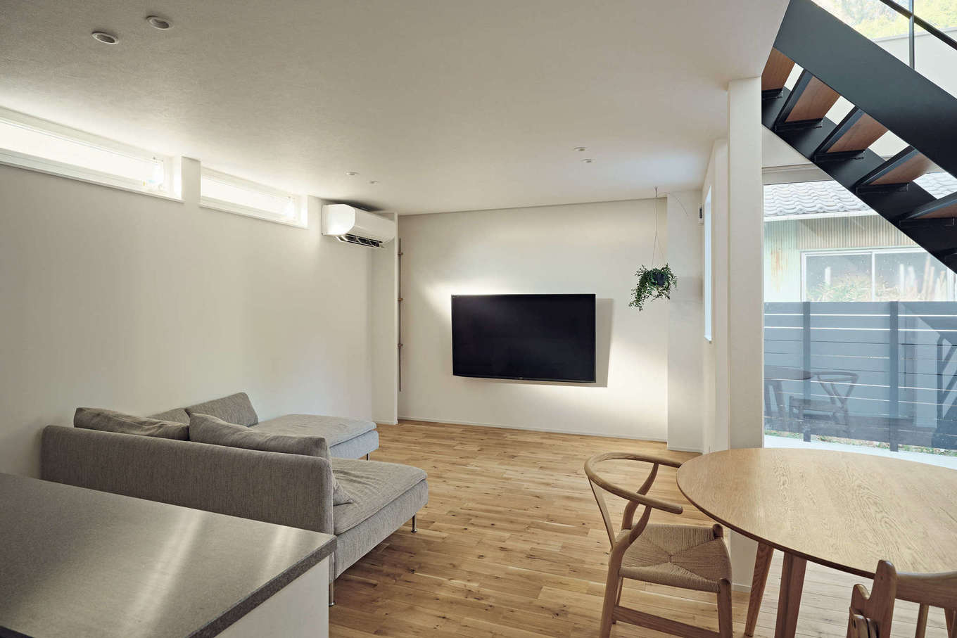 平屋建築ブルーハウス【デザイン住宅、建築家、平屋】大開口とハイサイドライトの両面から光が注がれ、明るさと開放感に満たされたリビング。ナラの無垢床の温かみを感じながら、リラックスしてくつろげる