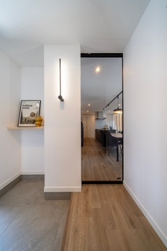 シンプルで洗練された玄関ホール。天井まで届く透明のリビングドアに視線が抜けて、より開放感が生まれた。ポール型の照明がアクセントに