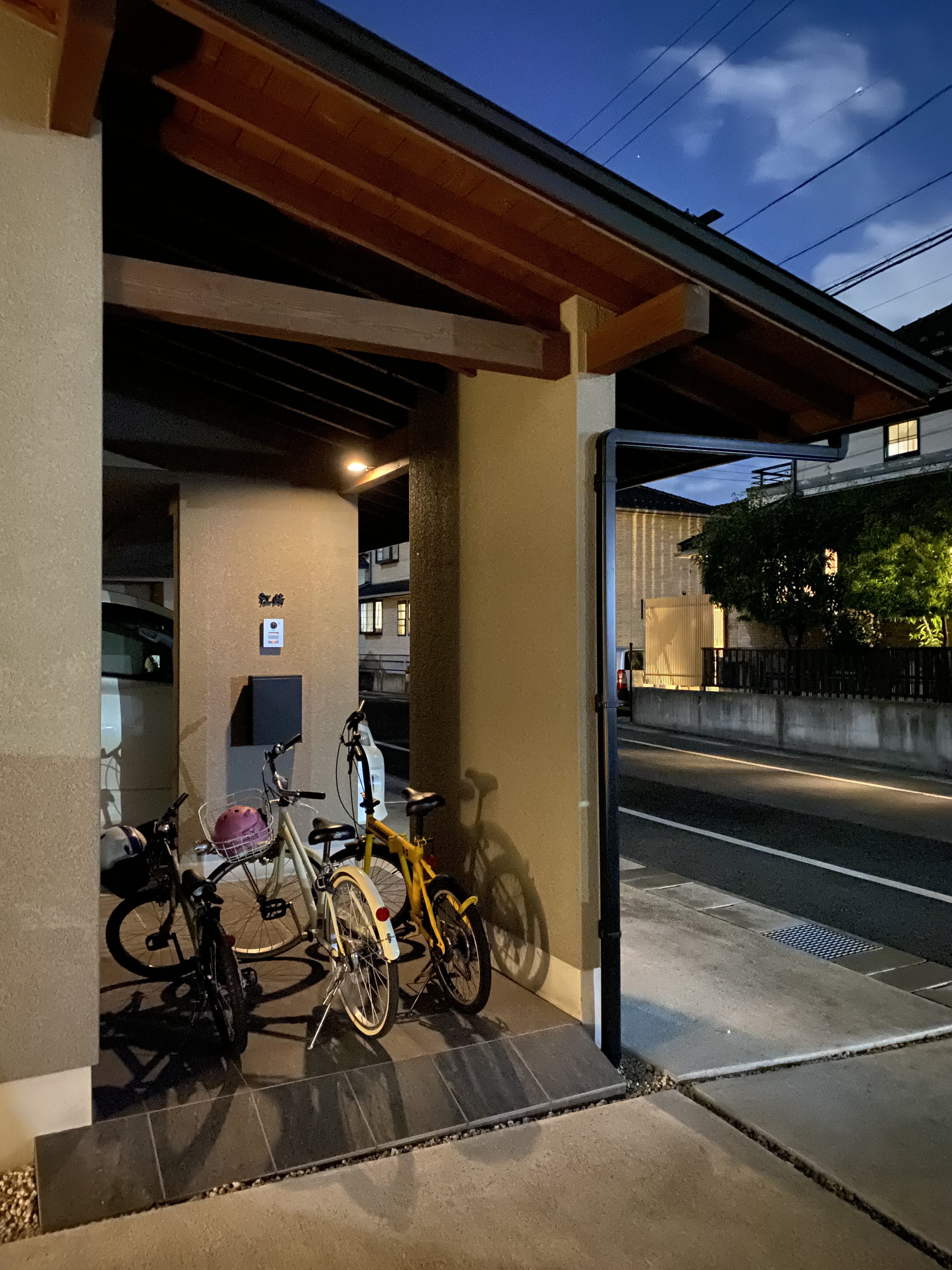 安田住宅｜安田建築設計室｜家の一部として設計されたアプローチ内に駐輪場を計画。道路から直接アクセスでき、夕暮れ時の雰囲気が落ち着いた印象を与える。