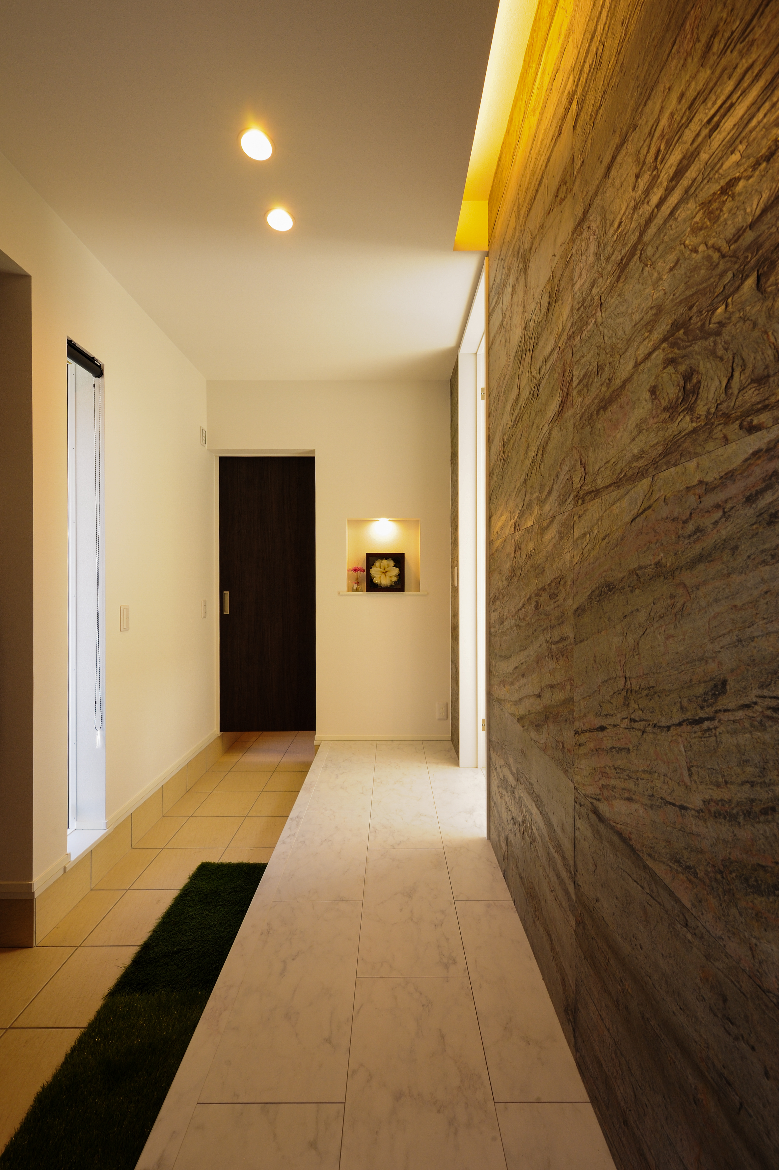 REIWA HOUSE（令和ハウス）｜「玄関の印象がいいと、その先も2～3倍良く見てもらえます。」と、Kさん。
玄関を入って最初に目に付く壁は本物の石を使用。
石の質感を浮かび上がらせる間接照明で高級感ある仕上がりに。