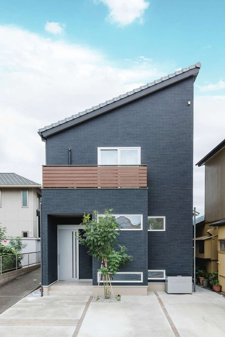 子育て安心住宅 Design Craft Office【デザイン住宅、子育て、狭小住宅】片流れの屋根のシャープなフォルムとブラックの外壁がスタイリッシュな外観。家が立ち並ぶ市街地の住宅街で一際インパクトを放つ。玄関の正面の扉の奥は外部物入れになっている