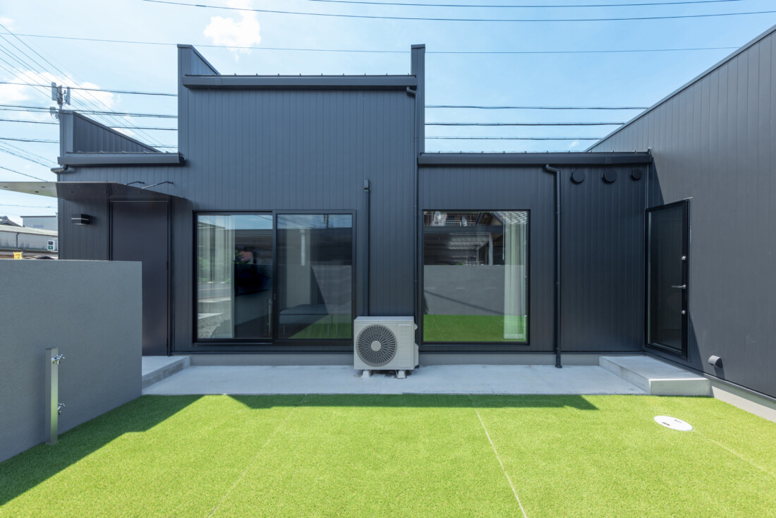 チェックハウス｜モダンなデザインの外観。機能的な一階建ての住宅で、広々とした人工芝の庭が特徴的