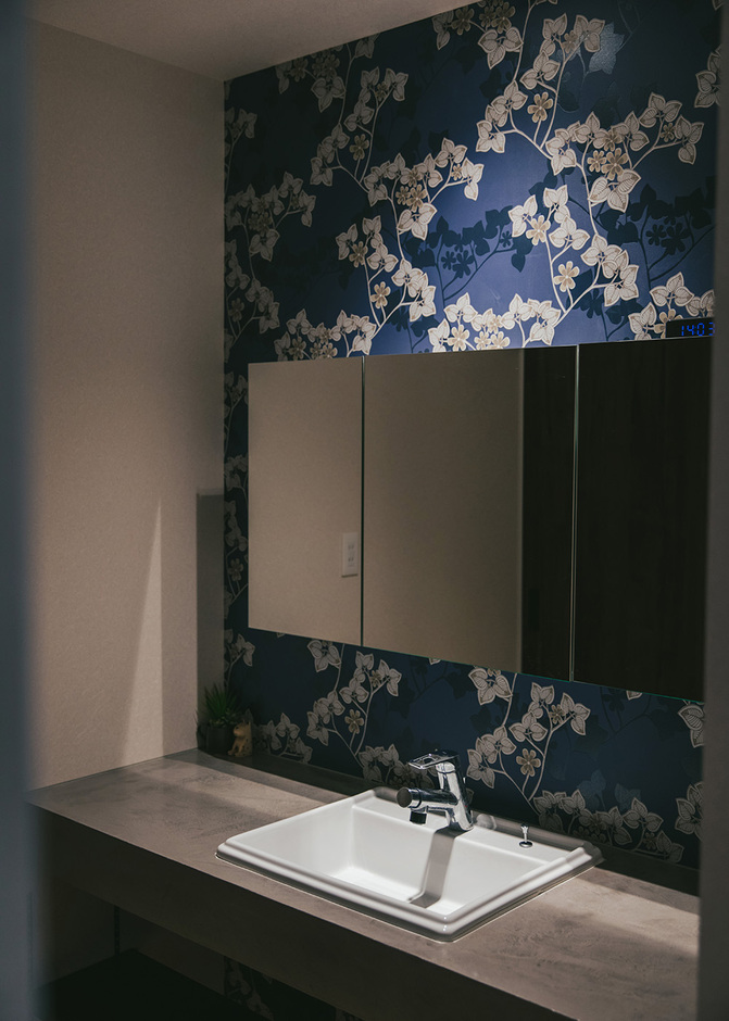 キッチン裏の水回り動線は洗面、トイレ、脱衣所、浴室が一列に並ぶ。幅の広い洗面台は造作によるもので、壁紙は奥さまが北欧カラーをイメージしてセレクト