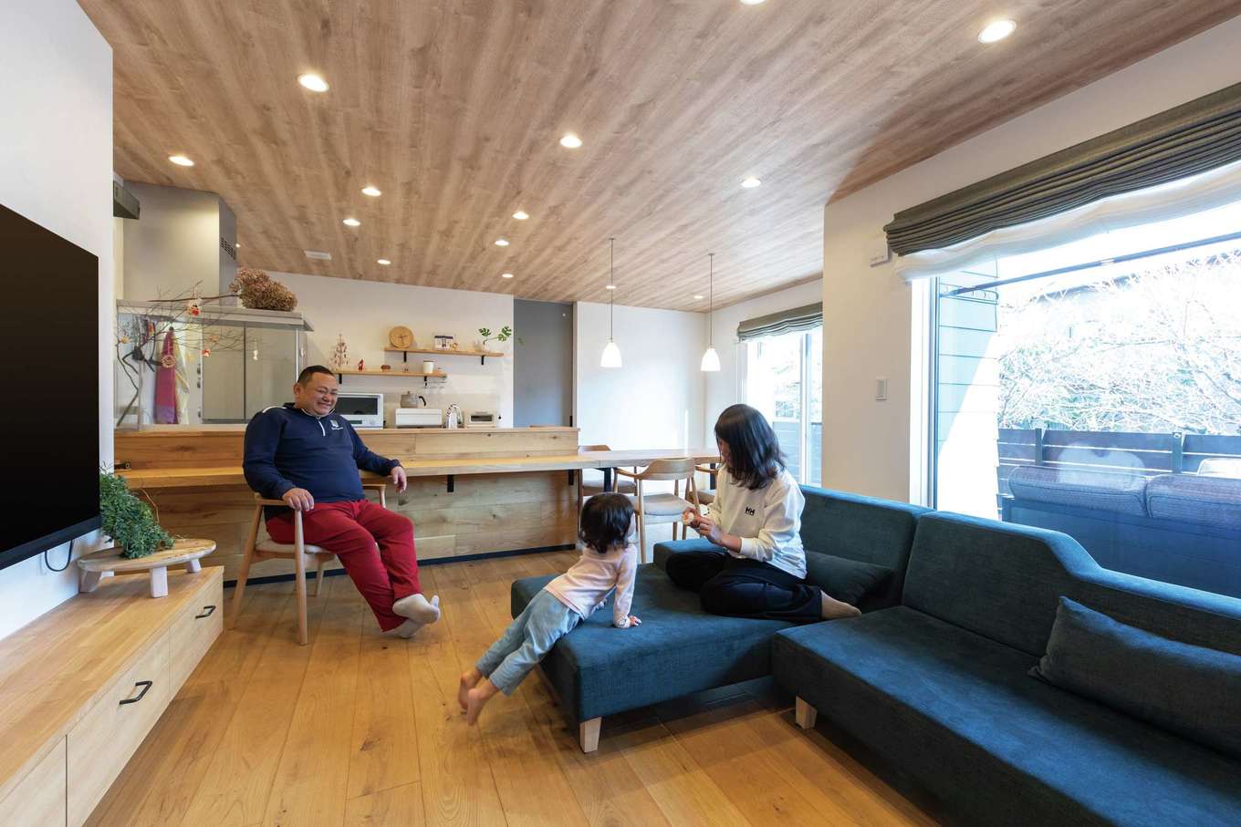 KUREKEN HAUS（榑林建設）【デザイン住宅、省エネ、間取り】無垢のあたたかみと窓から運ばれる開放感がブレンドされ、居心地のいいLDKが完成した。テレビ台も雰囲気に合わせ造作に。断熱性を左右する窓には、国内最高水準の性能を誇るLIXILのTWシリーズを採用。「家中温度差がなく、冬でも薄着で過ごせます」とご主人