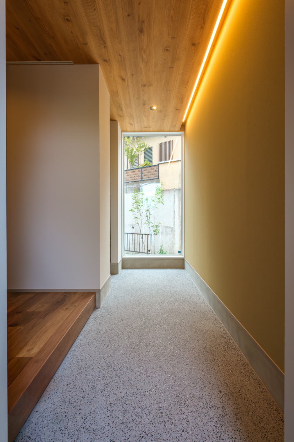 新栄建設｜自然光が差し込む明るい玄関。天井にも木目を採用したナチュラルなデザイン。正面のFIX窓から庭の緑が見え、心地よい空間を提供している。