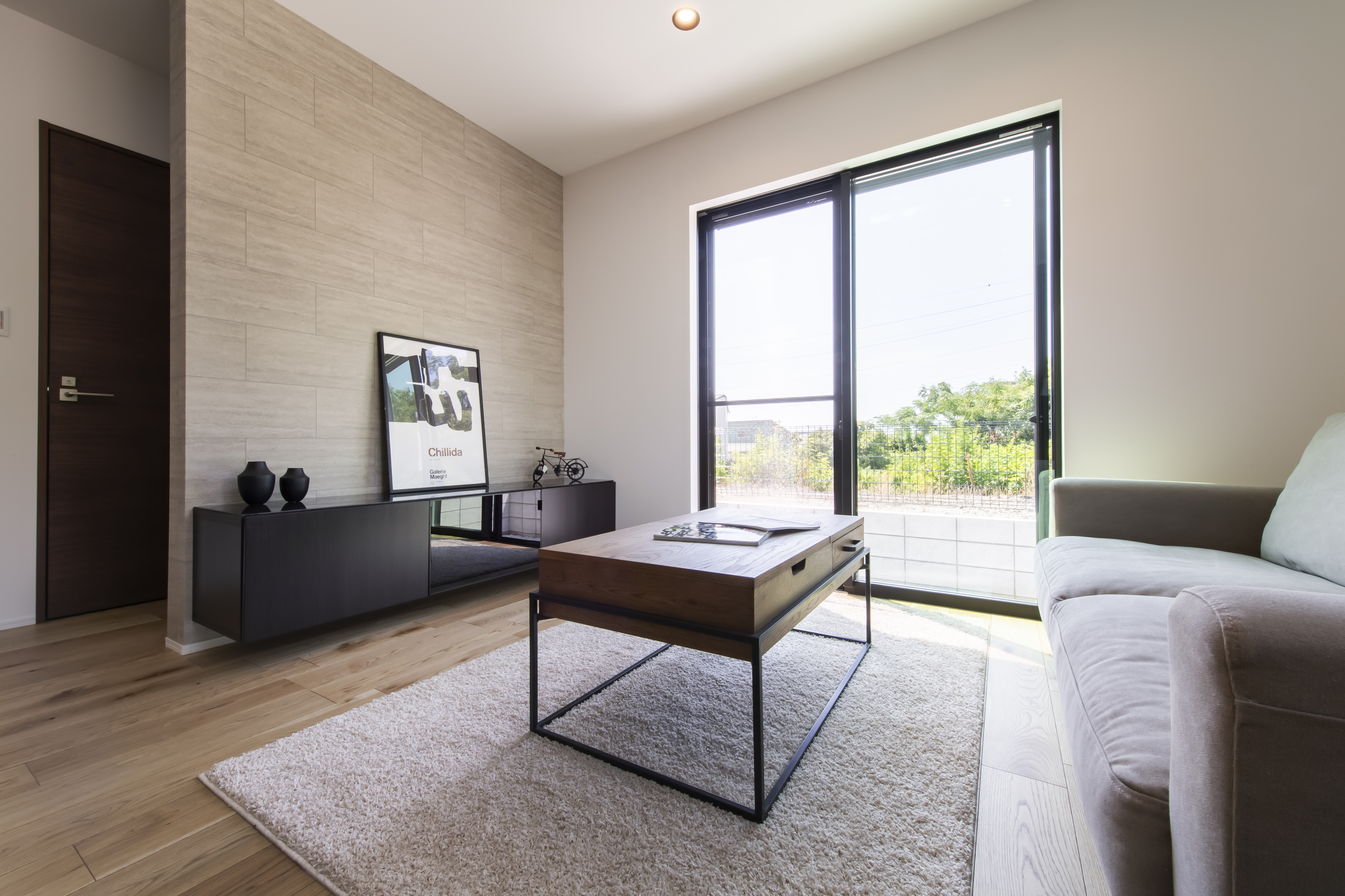 スズイチ｜モダンなデザインのリビングルーム。外光が十分に差し込む大きな窓があり、明るく快適な空間を演出している。