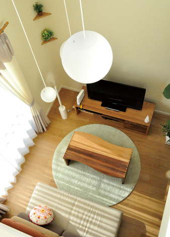 吹抜けの上部にはボール状の照明があり、やさしくリビングを照らす。木のぬくもりを感じる無垢の床や家具があたたかな気持ちにさせてくれる