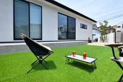 青々とした芝生が広がる庭。リラックスできるアウトドアスペースとして、椅子とテーブルを配置し、休日のくつろぎ時間に最適。