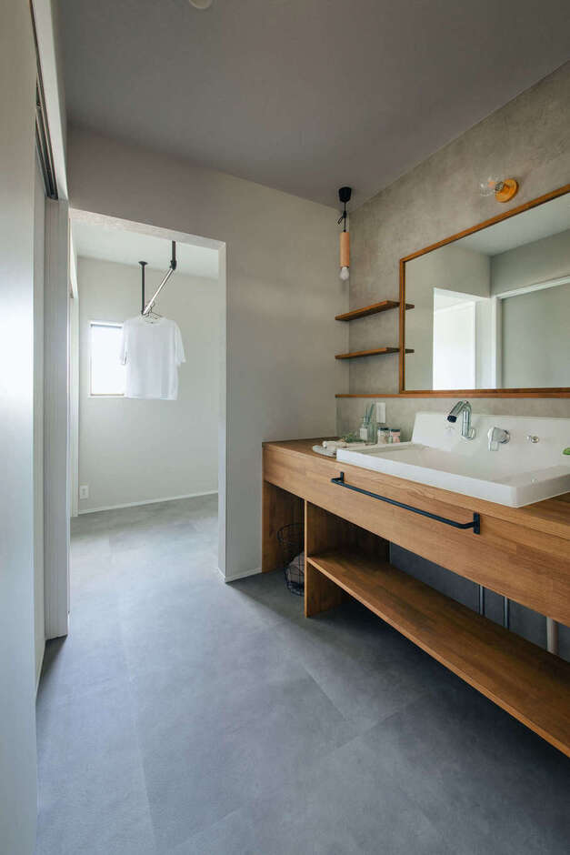 キッチンから流れるようにアクセスできるサニタリースペース。造作洗面台〜ランドリールームへとつながる動線が、家事時間を短縮してくれる