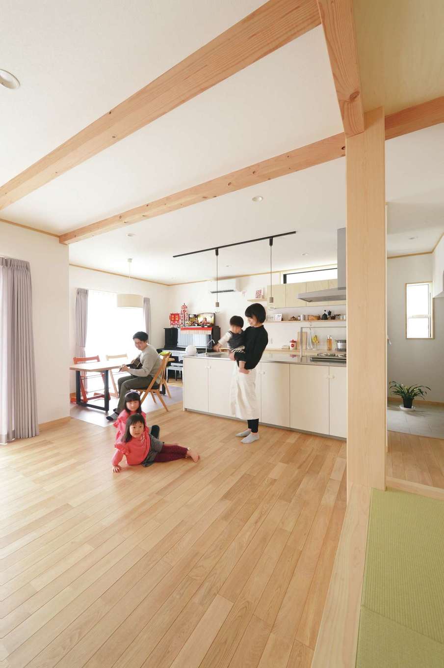 深見工務店 S-style【子育て、自然素材、間取り】無垢のナラ材とカルクウォールを使ったLDK。夏はサラッと涼しく、冬は素足で過ごせるほど暖かい。小上がりの畳コーナーは、子どもの昼寝や洗濯物をたたむときも便利。太いヒノキの大黒柱が子どもたちの成長をやさしく見守る