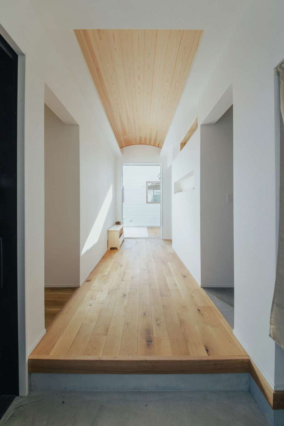 内田建設【デザイン住宅、建築家、平屋】ゆったりとした玄関ホール。天井の杉板をRに曲げて柔らかい雰囲気を醸し出した。正面奥のFIX窓越しにシンボルツリーを置く予定。ここから右側に進むとLDKと水回り、左側に進むと主寝室、子ども部屋のプライベートゾーンになっている