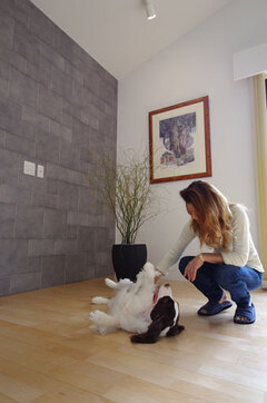 エコカラットタイル壁の前で愛犬と遊ぶ建築主さん。エコカラットタイルとはペットのニオイを吸収し、湿度も調整してくれる優れもののタイル。リビングと脱衣室の壁でこのタイルを採用している