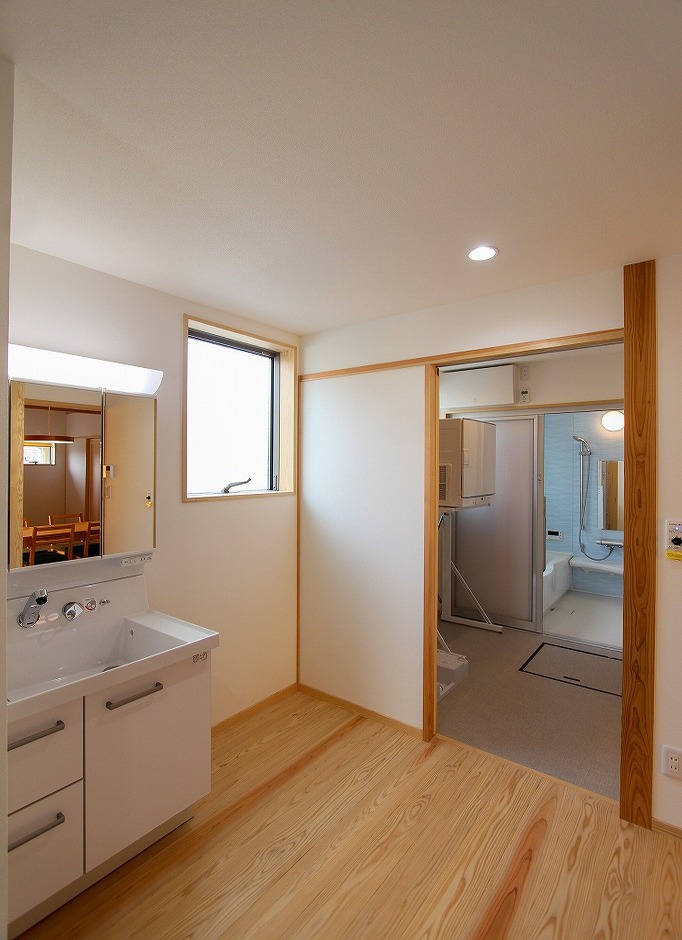 アクトホーム【自然素材、省エネ、間取り】洗面・浴室・トイレとランドリールームをまとめた空間。室内干しのスペースだけではなく、屋根付きの物干しテラスにつながる勝手口も設けた。