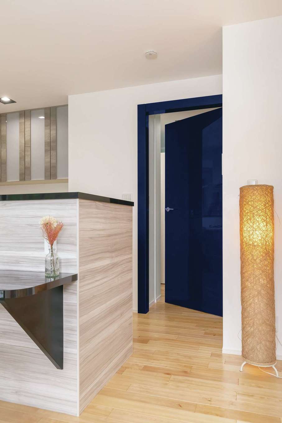 nattoku住宅｜ドアもインテリアの一部と考える『納得住宅工房』。イタリア製のリビングドア「レーベル」は、鏡面のようなきらめきと蝶番のない美しいフォルムが特徴で、三ツ星レストランやホテルでも採用されているほど。研磨と塗装を繰り返して生まれる輝きと重厚感が空間をラグジュアリーに引き立てる。カラーラインナップは10種類から選べて、W邸はネイビーを選択