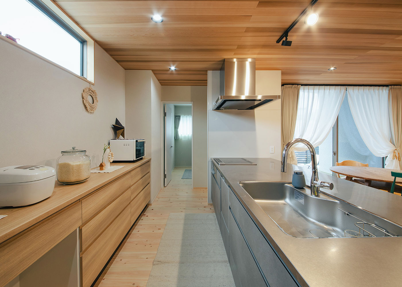 フジモクの家（富士木材）【子育て、自然素材、平屋】キッチンはアイランドスタイル。開放的で回遊しやすく、スムーズに作業できるようになったため、家事効率がアップした。正面のドアの先は子ども部屋