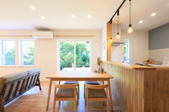 大きな窓から光が差し込む明るいLDK。木目調の家具とペンダントライトが温かみを感じさせ、リラックスできる空間を演出している。