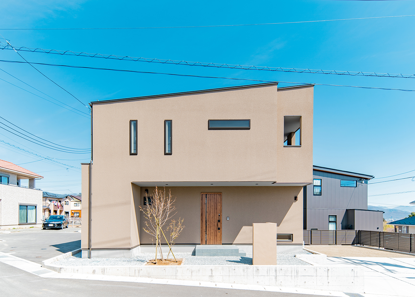 クリエイティブスタジオ [SAW] -ソウ-【デザイン住宅、趣味、狭小住宅】土地の形状や高低差を活かして設計された二階建ての住まい。敷地の低い面に駐車場と庭を設けて、眺望を楽しめるよう配慮した